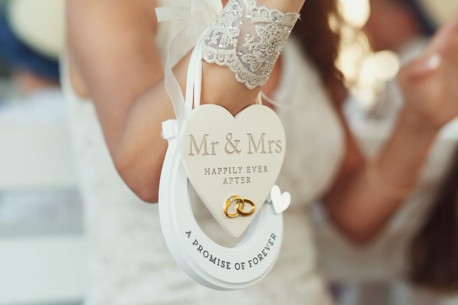 A bride holding a Mr and Mrs wedding keepsake with the rings